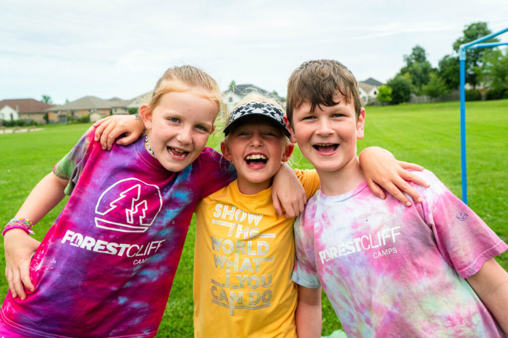 Kids laughing in a field at summer camp.